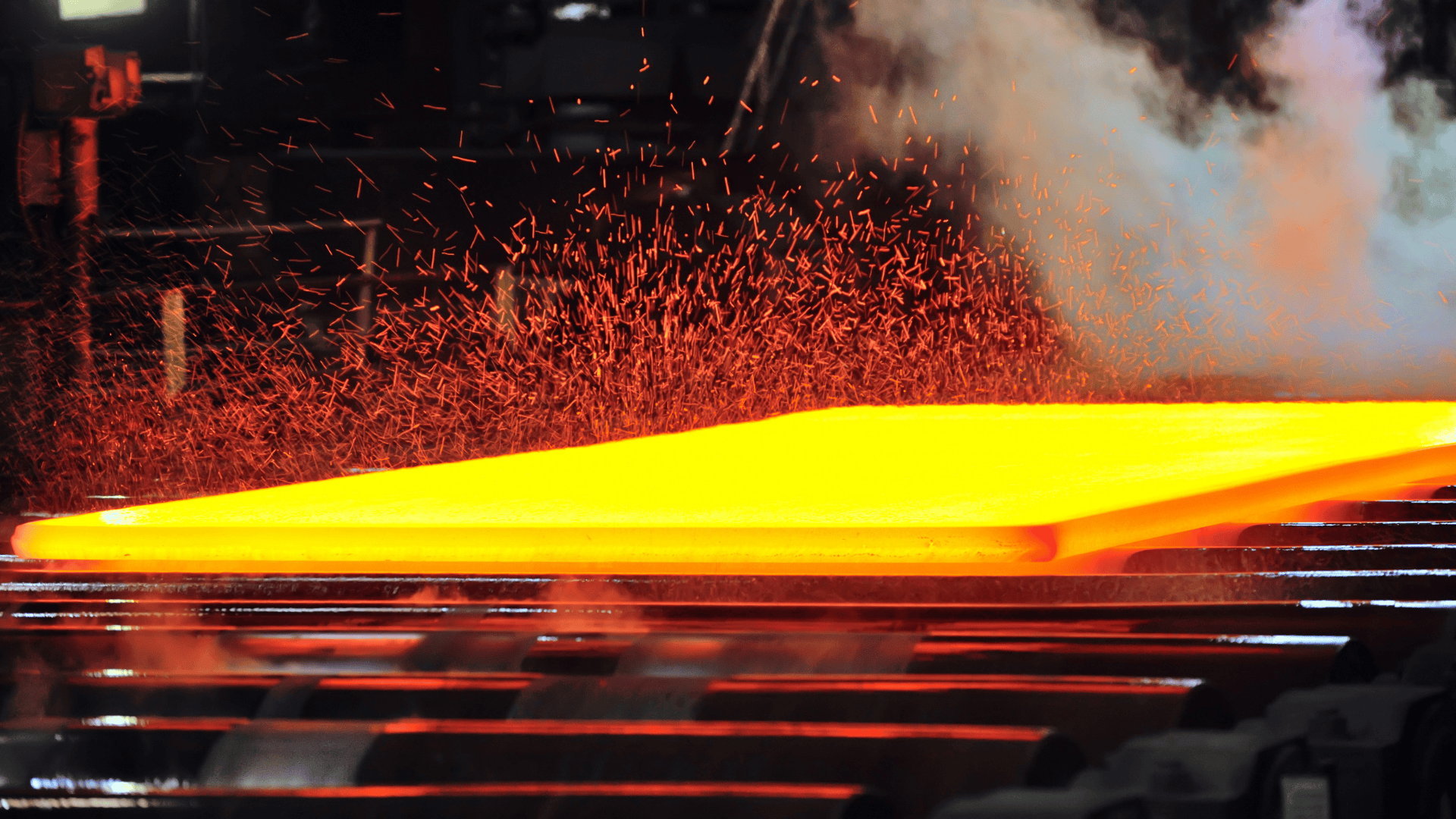 Hot metal being processed in a forge, glowing yellow with sparks.