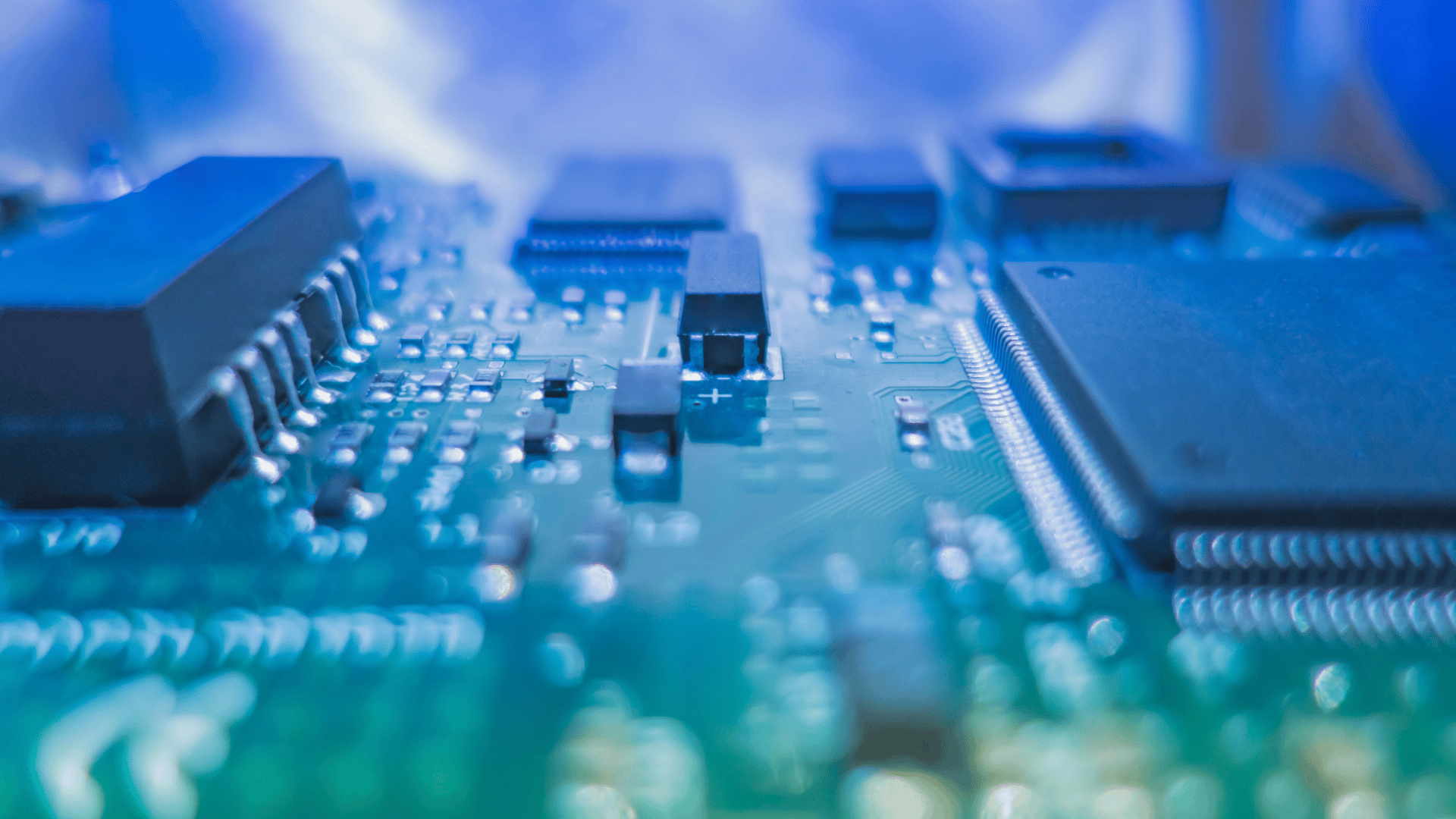 Close-up view of a blue electronic circuit board with microchips and components.