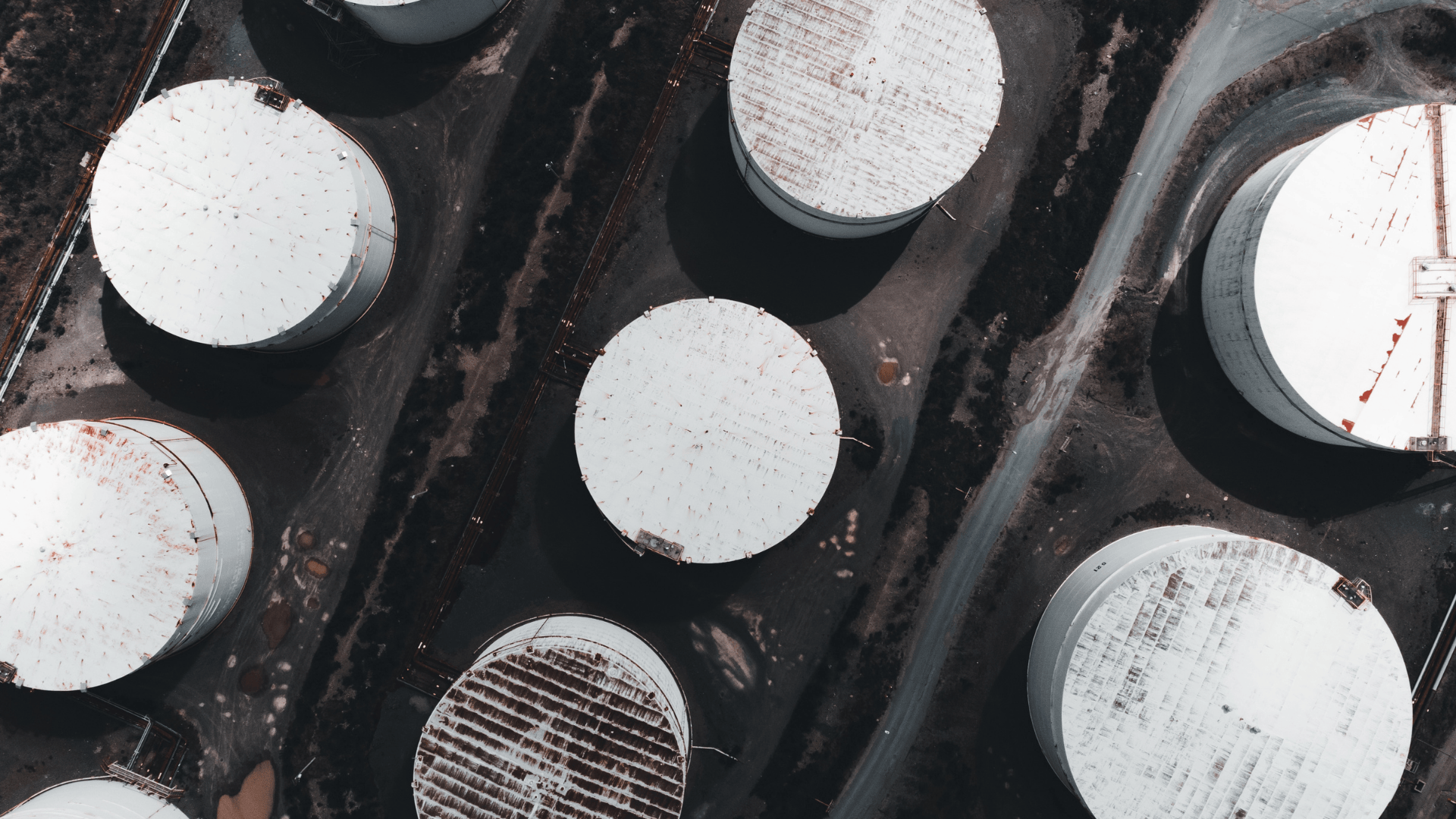 Aerial view of large industrial storage tanks in an oil or fuel facility.
