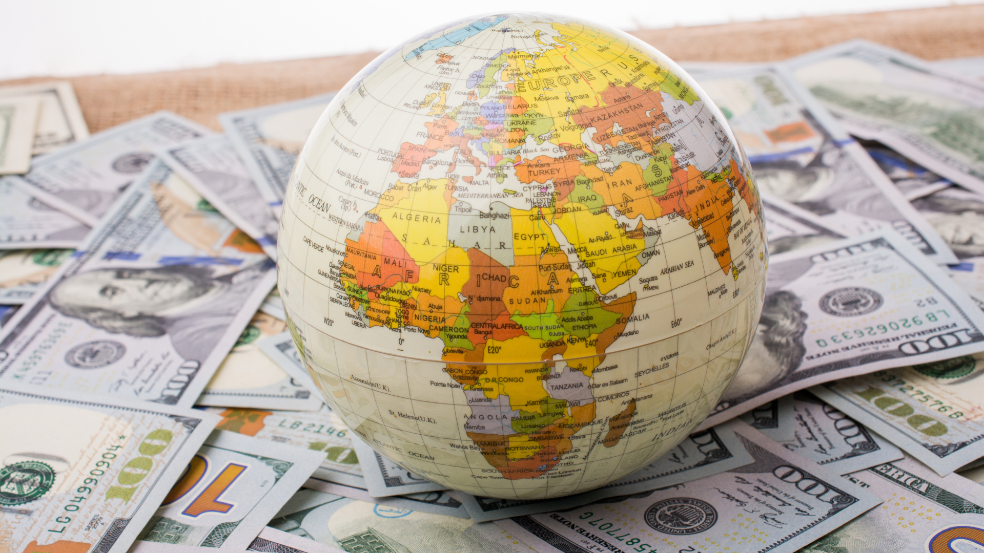 A globe showing Europe, Africa, and the Middle East placed on top of scattered US dollar banknotes, symbolising global finance and international markets.