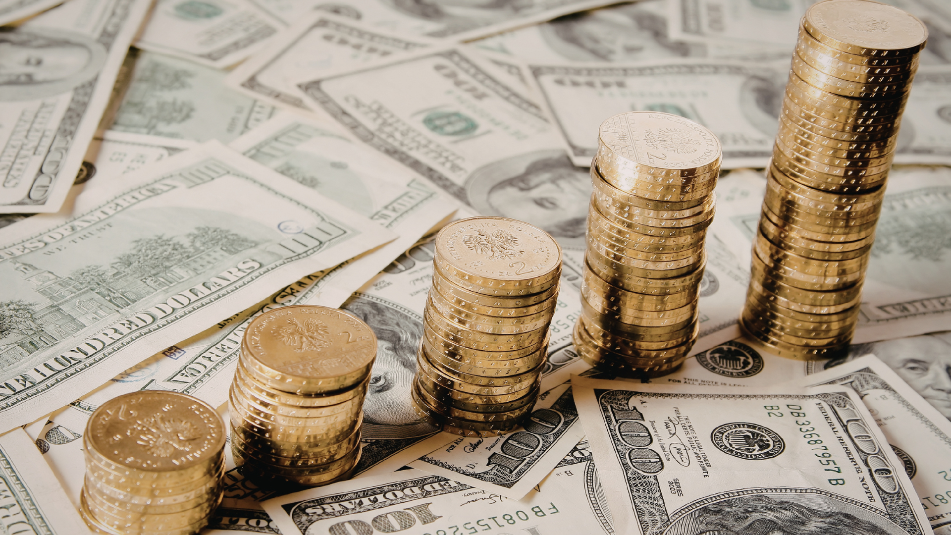 Stacks of gold coins on us dollar bills
