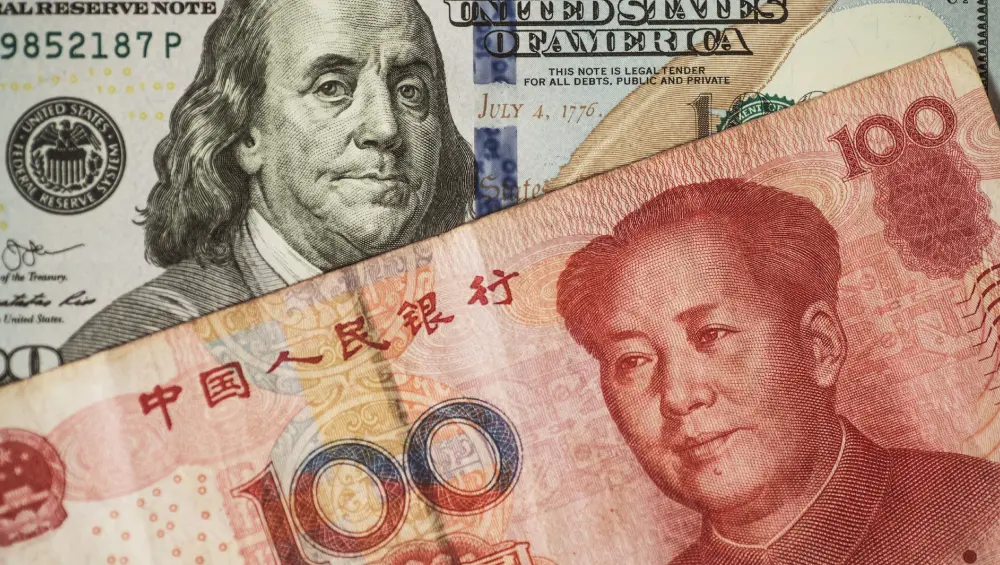 A US $100 bill featuring Benjamin Franklin placed behind a Chinese 100 Yuan (Renminbi) banknote featuring Mao Zedong, representing the USD/CNH currency pair.